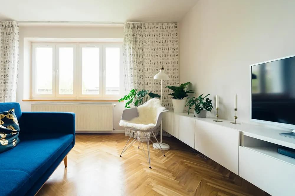 Wohnzimmer mit Fischgrätparkett und blauem Sofa